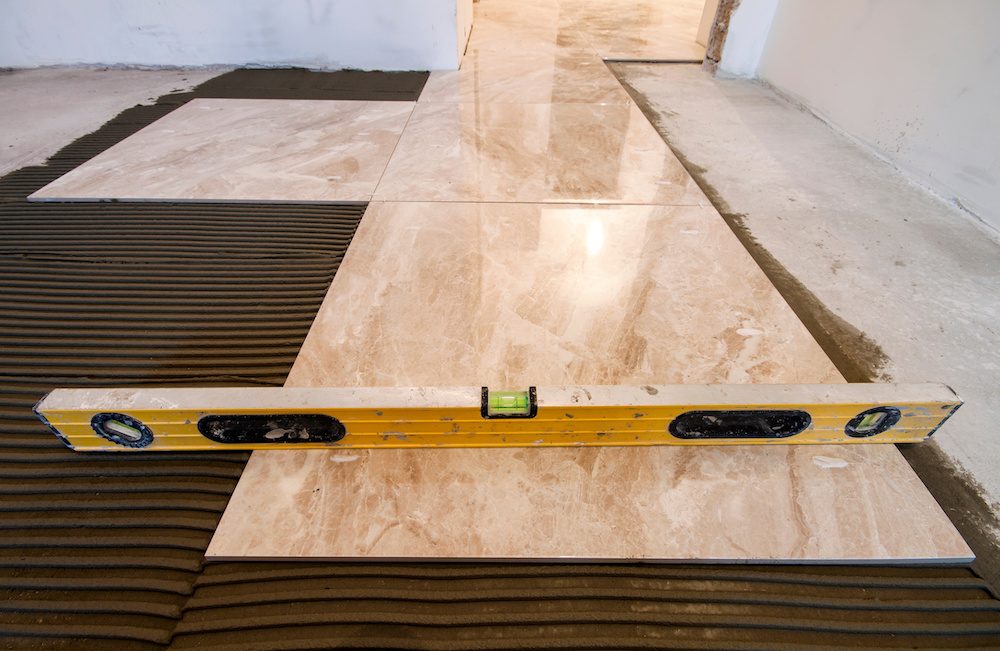 Ceramic tiles and tools for tiler. Floor tiles installation. Home improvement, renovation - ceramic tile floor adhesive,  mortar, level